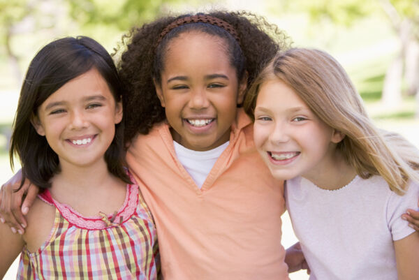 Three young girl friends outdoors smiling